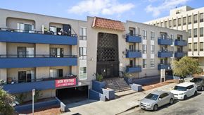 Los Angeles apartment for rent - A building with a sign that says "Now Renting" is in front of a car.