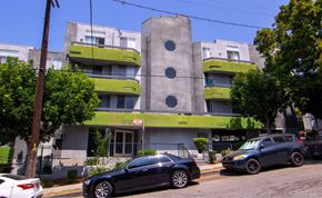 Los Angeles apartment for rent - A black car is parked in front of a grey and green building.