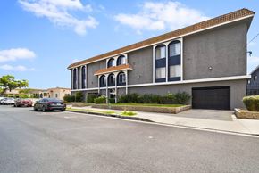 Hawthorne apartment for rent - A grey building with a red roof and a black car parked in front.