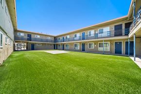 Hawthorne apartment for rent - A sunny day at the courtyard of a building with blue doors and windows.
