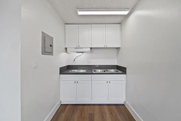 Pico Rivera apartment for rent - A kitchen with white cabinets and a black countertop.