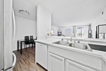 Los Angeles apartment for rent - A white kitchen with a black chair and a white fridge.