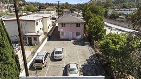 Los Angeles apartment for rent - A parking lot with several cars and a pink house in the background.
