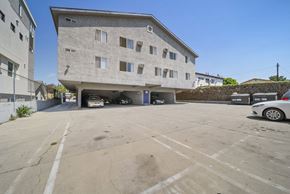Los Angeles apartment for rent - A parking lot in front of a concrete building with a car parked in it.