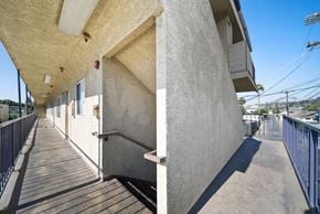 Los Angeles apartment for rent - A long concrete building with a wooden walkway in front.