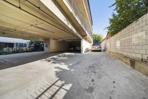 Los Angeles apartment for rent - A concrete parking area under a bridge with a car parked in the distance.