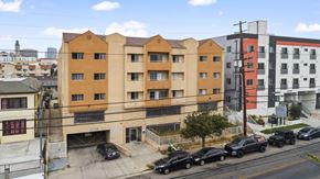 Los Angeles apartment for rent - A street view of a multi-story building with cars parked in front.