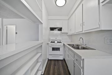 Hawthorne apartment for rent - A modern kitchen with white cabinets and a wooden floor.