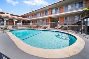 Hawthorne apartment for rent - A swimming pool in front of a building with orange and white walls.