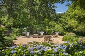 Piscataway apartment for rent - A garden with tables and chairs surrounded by trees. at Rivercrest Apartments, Piscataway  08854