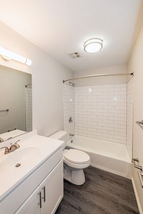 Camillus townhouse for rent - Fully renovated bathroom with subway tile, gray plank flooring, and white vanity at Kings Gate West Apartments, Camillus, NY, 13031