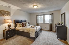 Camillus townhouse for rent - A bedroom with a large bed and a nightstand with a lamp at Kings Gate West Apartments, New York
