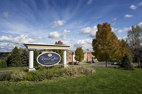 Camillus townhouse for rent - A Kings Gate Apartments sign is in front of a building and trees at Kings Gate West Apartments, Camillus 13031