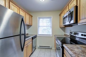 Piscataway apartment for rent - A kitchen with a stainless steel refrigerator and wooden cabinets.