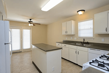 A kitchen with white appliances and a ceiling fan