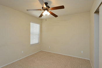 A bedroom with a ceiling fan and a window