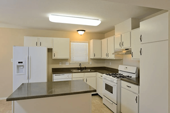 A kitchen with white cabinets and appliances and a counter top