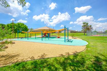 A playground with a blue and yellow swing set on a sunny day
