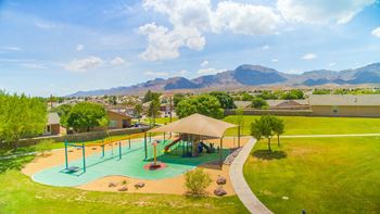 An aerial view of a playground with houses and mountains in the background