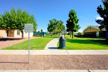 A sidewalk in front of a park with a street sign