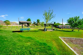 A playground with two swings and a swing set in a park
