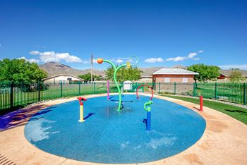 A childrens pool with water toys in a fenced in yard