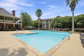 Lafayette apartment for rent - A large swimming pool surrounded by a concrete patio and a building with a balcony.