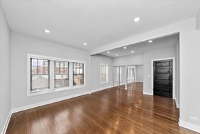 Chicago apartment for rent - A spacious room with wooden floors and white walls.