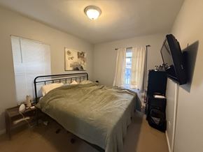Chicago apartment for rent - A bedroom with a bed, nightstand, and window with blinds.