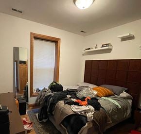 Chicago apartment for rent - A bedroom with a messy bed and a window with blinds.