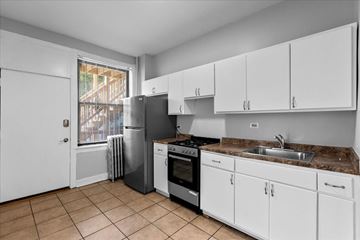 Chicago apartment for rent - A kitchen with white cabinets and a brown countertop.