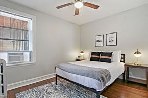 Chicago apartment for rent - A bedroom with a bed, two lamps, and a ceiling fan.