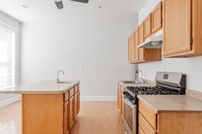 Chicago apartment for rent - A kitchen with wooden cabinets and a stove top oven.