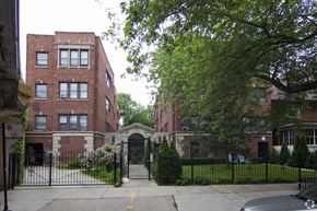 Chicago apartment for rent - the front of a red brick building with a black fence and a gate
