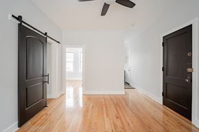 Chicago apartment for rent - an empty room with black doors and a wood floor and a ceiling fan