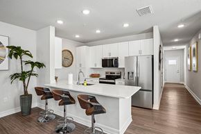 Tavares apartment for rent - A kitchen with white cabinets and a white island with brown bar stools.