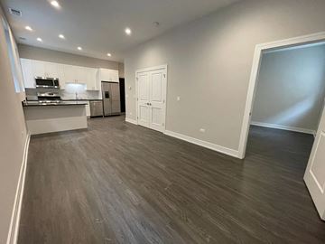 Chicago apartment for rent - A spacious kitchen with white cabinets and a dark wood floor.