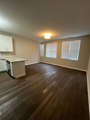 Chicago apartment for rent - an empty living room with a kitchen in the background