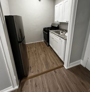 Chicago apartment for rent - A kitchen with a black fridge and white cabinets.