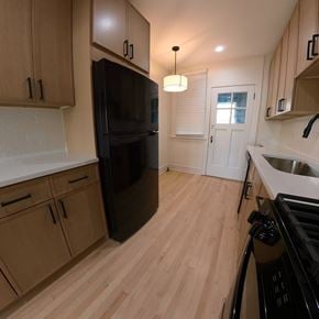 Chicago apartment for rent - A kitchen with a black fridge and wooden cabinets.