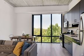 Chicago apartment for rent - A modern kitchen with a dining table and a couch with a view of trees outside.
