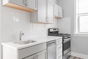 Chicago apartment for rent - a kitchen with white cabinets and a sink and a stove