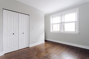 Evanston apartment for rent - a bedroom with white walls and wood floors and a window