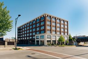 Chicago apartment for rent - A large brown building with many windows is situated on a street corner.