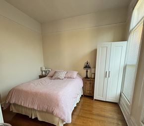 Chicago apartment for rent - A bedroom with a pink bedspread and a white wardrobe.