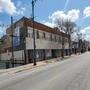 Chicago apartment for rent - A street view of a building with a blue sign on the left side.