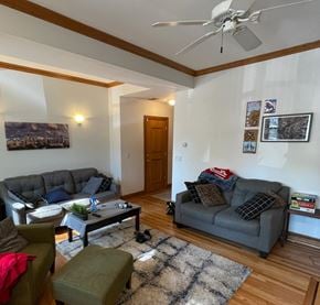 Chicago apartment for rent - A living room with a grey couch, a green ottoman, a coffee table, and a ceiling fan.