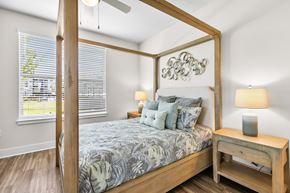 Kissimmee apartment for rent - A bedroom with a four poster bed and a wooden nightstand.