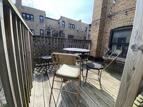 Chicago apartment for rent - a balcony with a table and chairs and a brick building