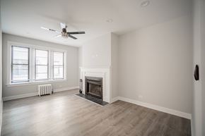 Chicago apartment for rent - A spacious living room with a fireplace and a ceiling fan.
